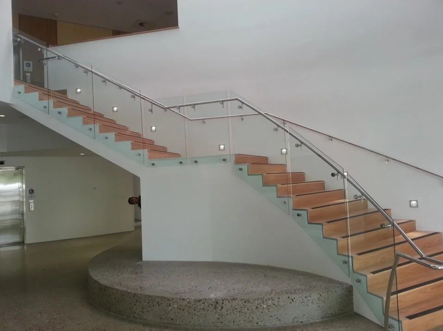 Semi-frameless glass balustrade on a curved staircase with stainless steel handrail and point fixings