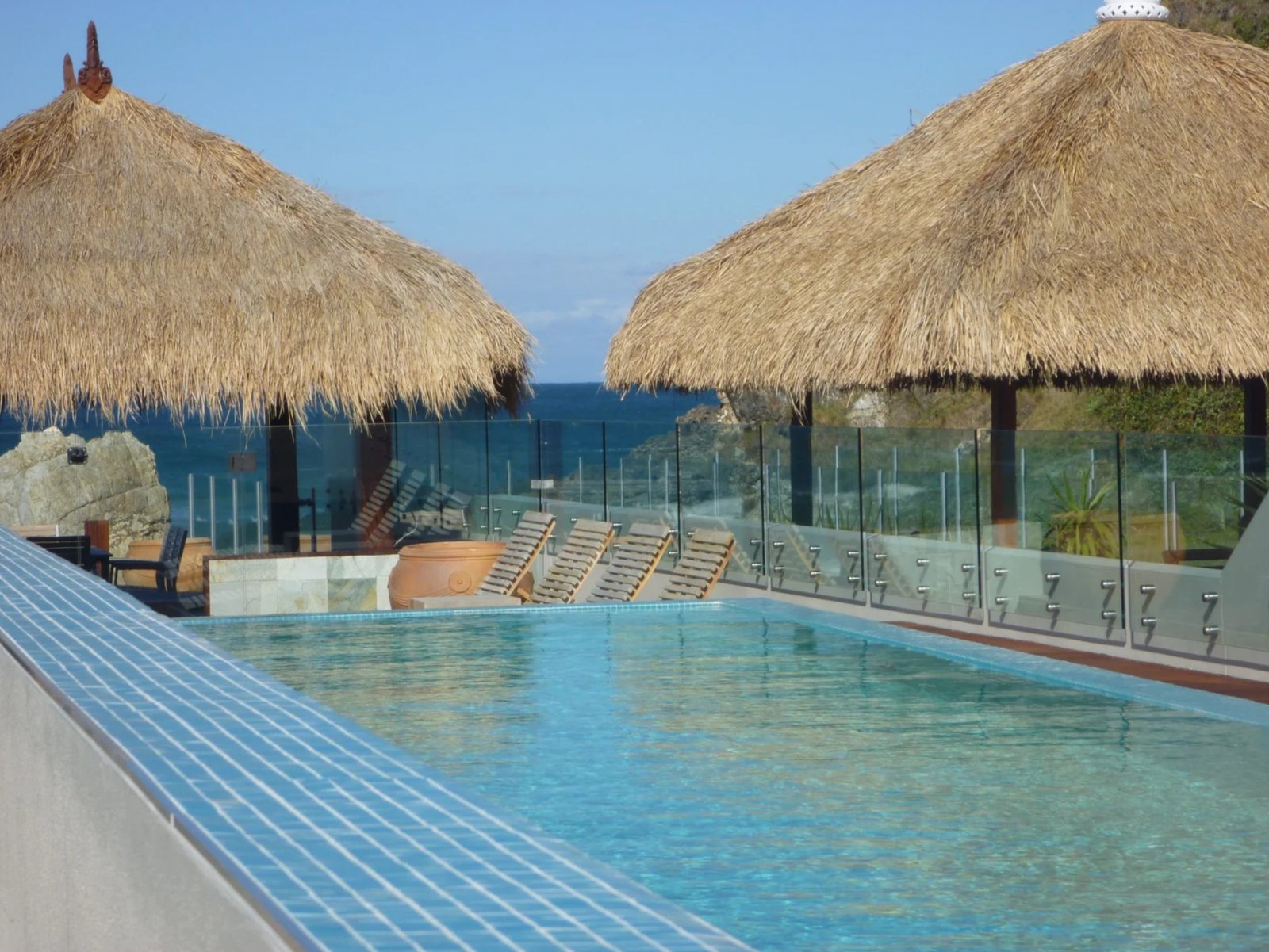 Frameless glass pool fencing around a coastal infinity pool with ocean views, by Harbour Glass
