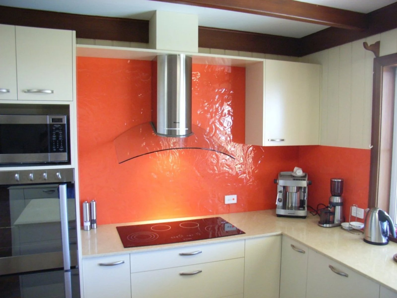 Vibrant orange painted glass splashback installed in modern kitchen by Harbour Glass